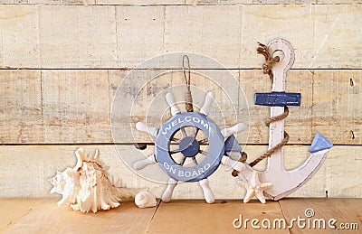 Old nautical wood wheel, anchor and shells on wooden table over wooden background. vintage filtered image Stock Photo