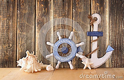 Old nautical wood wheel, anchor and shells on wooden table over wooden background. vintage filtered image Stock Photo