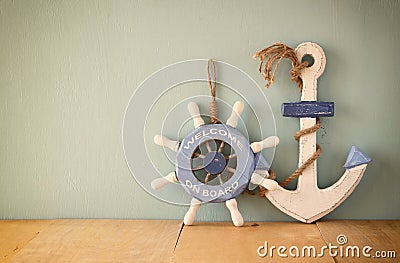 Old nautical wood wheel and anchor on wooden table over wooden aqua background Stock Photo