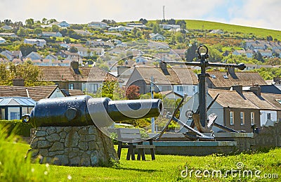 Old naval fortifications and cannons with rusty anchor as landmark and tourist attraction in Wicklow port and village in backgroun Stock Photo