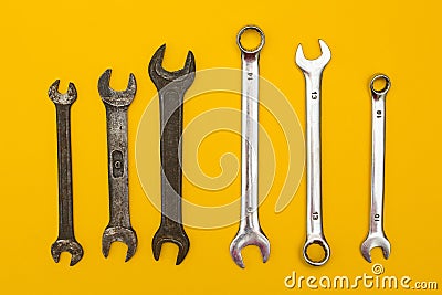 Old and new wrenches on a yellow background Stock Photo