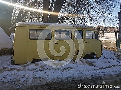 Old non-working car in the snow under a tree Stock Photo