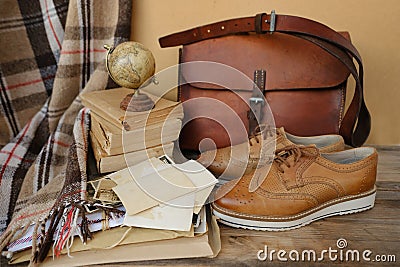 old nostalgic sentimental things, family vintage photographs, stack of books, shoes, leather military satchel on table, checkered Stock Photo