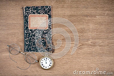 Old notebook, retro eye glasses and vintage pocket watches on oak textured wooden table background Stock Photo