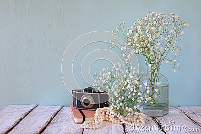 Old notebook, white pearls necklace next to old photo camera on wooden table Stock Photo