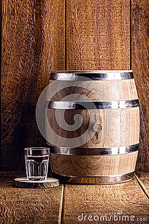 Old oak barrel and glass of high quality distilled alcohol. Brazilian silver cachaÃ§a, called pinga, vodka, white rum, liqueur, Stock Photo