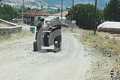 Old orange Tractor of brand Turk Fiat driving with three wokers Editorial Stock Photo