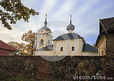 Old Orthodox church behind natural stone wall against background of the northern autumn sky Stock Photo