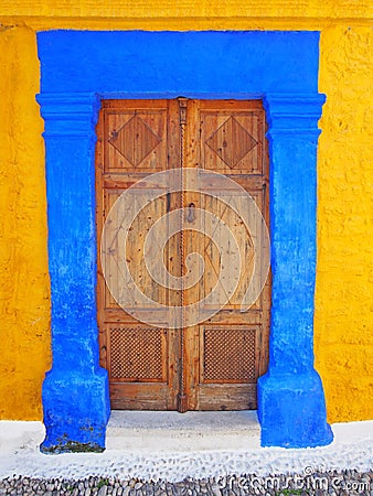 Ottoman style ornate wooden door double in a bright blue painted stone frame set in a yellow wall in rhodes town greece Stock Photo