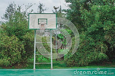 Old outdoor basketball court in the park with green natural in the background. Stock Photo