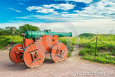 An old oxidized metal cannon with wooden wheels painted in red. Oslo, Norway Stock Photo