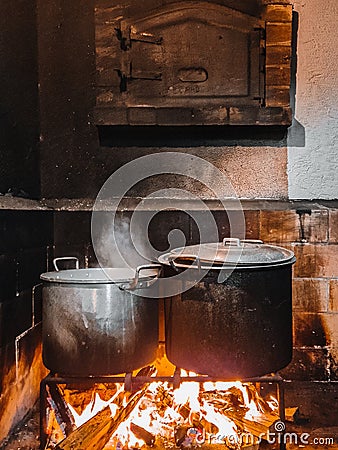 Old pans simmering on a rustic fireplace Stock Photo