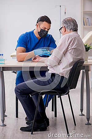 Old patient visiting young male doctor in blood transfusion conc Stock Photo