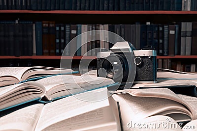 Old photo camera is on many open books piled up with many book Stock Photo