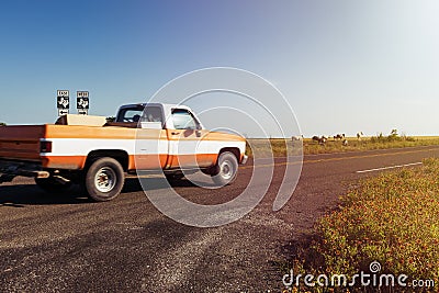 Old pickup truck riding along a farm road with a ranch and horses on the background at sunset in rural Texas Stock Photo