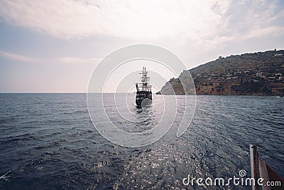 Old pirate ship on the water of Mediteranean sea. Tourist entertainment, coastal tour. Summer sunny day. Mountain shore of Alanya Editorial Stock Photo