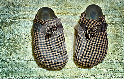 Old plaid worn slippers on an old carpet Stock Photo