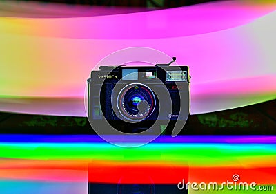 An old point and shoot film camera. Photograph painted in rainbow colours using light painting technique. Editorial Stock Photo