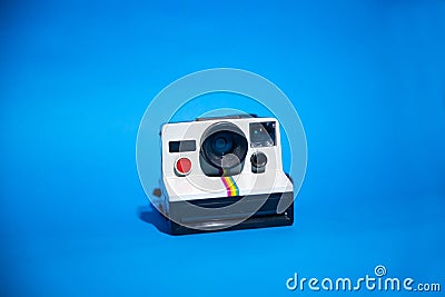 Old Polaroid camera isolated on a blue background Editorial Stock Photo