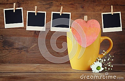 Old polaroid photo frames hanging on a rope with coffee cup and cookies over wooden background Stock Photo