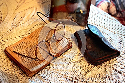 Old Polish Bible, retro spectacles and vintage mirror on a tablecloth. Old age, senility and poverty concept. Editorial Stock Photo