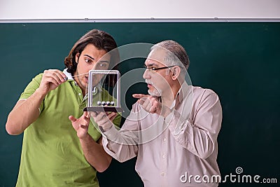 Old professor physicist and young student in the classroom Stock Photo