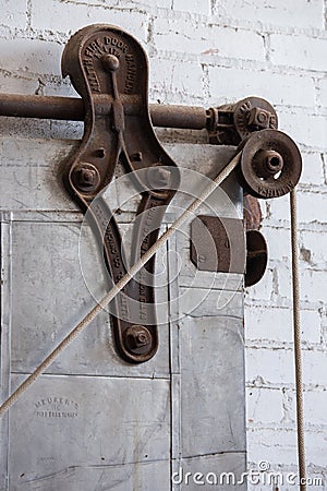 Old pulley on metal sliding industrial door in old warehouse Editorial Stock Photo