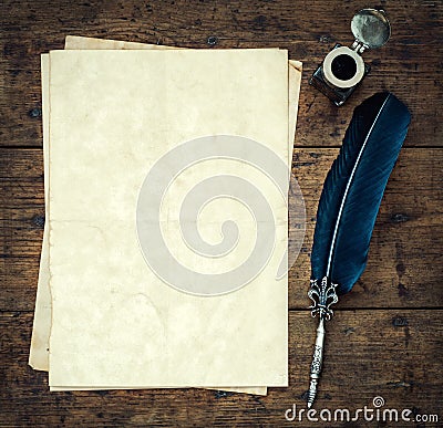 Old quill pen, and old paper blank sheet and vintage inkwell on wooden desk in the old office . Retro style. Conceptual background Stock Photo