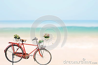 Old red Bicycle with basket flowers on blured beach tropical sea Stock Photo