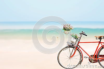 Old red Bicycle with basket flowers on blured beach tropical sea Stock Photo