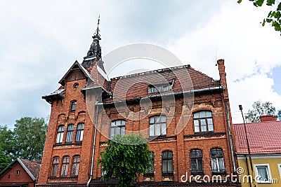 An old red brick house. Part of the red brick wall, windows and a fragment of the roof of an old residential building against the Stock Photo