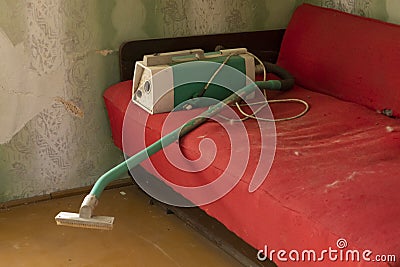 Old red couch and a vintage vacuum cleaner Stock Photo