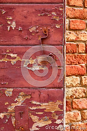 Old red cracky wooden door with flacky paint rusty metal handle Stock Photo