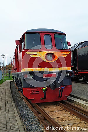 Old red diesel engine locomotive at the railway station. Vintage train staying on the railroad. Stock Photo