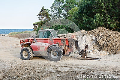 Red four wheel drive forklift tractor staying on a construction site. Stock Photo