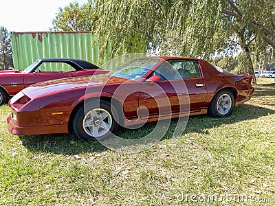 Old red sport Chevrolet Camaro coupe 1982 - 1992 by GM parked on the grass. Classic muscle car. Editorial Stock Photo