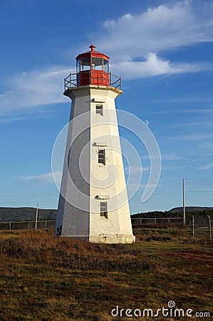 old red and white lighthouse on a field blue skies Stock Photo