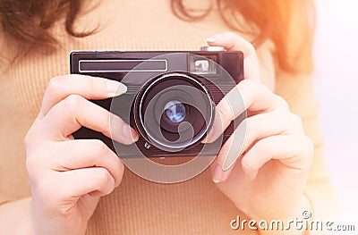 Old retro camera in the hands of photographer, close-up. Camera in female hands with yellow light Stock Photo