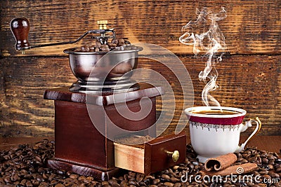 Retro coffee mill and cup with black coffee smoking on wooden background Stock Photo