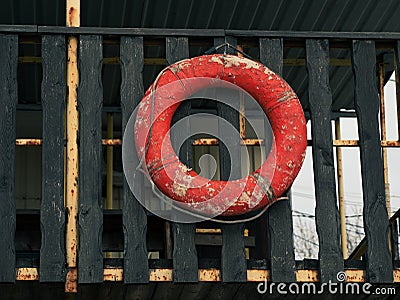 Old retro red lifebuoy hanging on wooden balcony. Help, rescue concept. Vintage life saver on the beach house Stock Photo