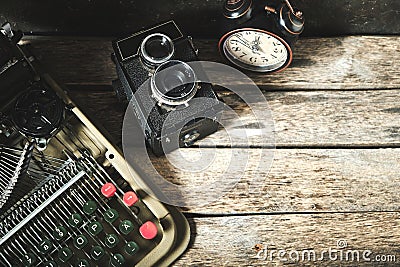 Old retro typewriter, alarm clock and camera on a wooden background top view Stock Photo