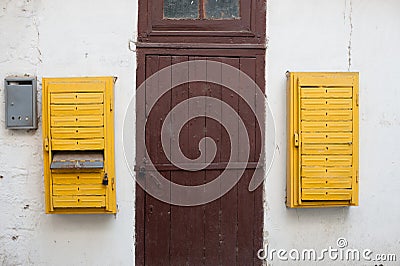 Old retro vintage exterior white wall with wooden door with lock and yellow opened mail boxes Stock Photo