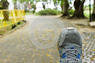 An old running shoe on a blurred park walkway background Stock Photo