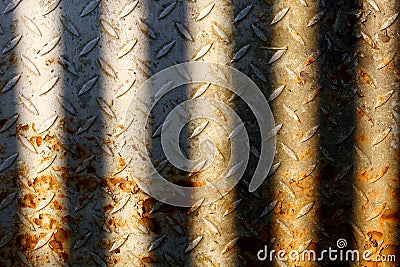 Old rusted metal plate sun-lit between bars Stock Photo