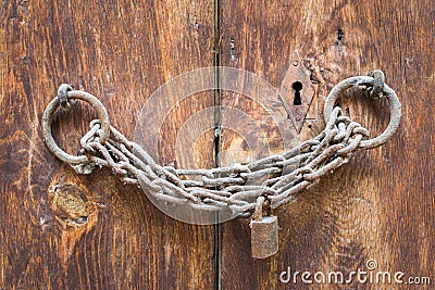 Old rusted padlock, rusted chain, and keyhole on a closed wooden door Stock Photo