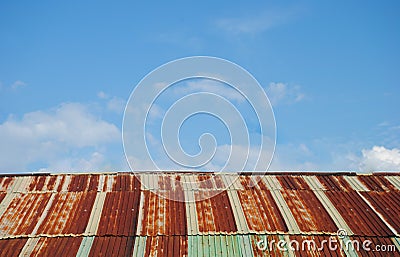 Old rusted and weathered steel quonset hut roof against a blue sky with fluff clouds Stock Photo