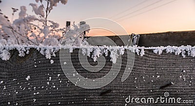 Old rustic fence covered with snow and hoarfrost evening sunset winter landscape cattle corral Stock Photo