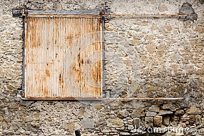 Old rustic solid metal sliding shutters in very old stone house Stock Photo