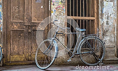 Old rusty bicycle at the doorway of a weathered house Stock Photo