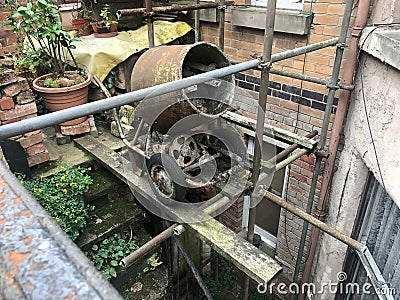 An Old Rusty Cement Mixer Suspended in the Air, Very Unsafely on Some Scaffolding Stock Photo